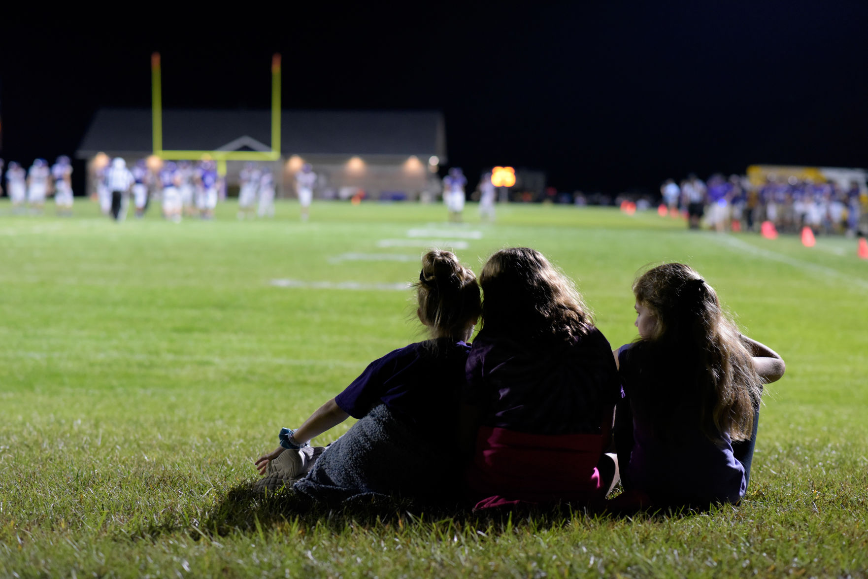 From left to right, Bella Abell, Keatyn Hogf and Ava Gilo, all 11 years old, watch a Hallsville High School varsity football game